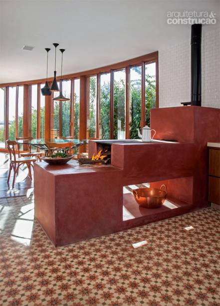 Revestido de vermelh&atilde;o, o fog&atilde;o a lenha lembra que a casa est&aacute; no interior de Minas Gerais. Ele separa a cozinha da &aacute;rea de apoio. Projeto dos arquitetos Marcelo Alvarenga e Jos&eacute; Ricardo Fois.