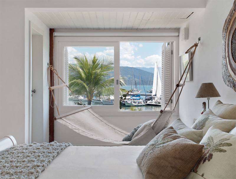 Rede no quarto. &Agrave; frente desta casa dentro de uma marina em Parati (RJ), um barco ancorado espera pelo jovem casal paulistano. O quarto, acima, incorporou a &aacute;rea de uma pequena varanda. Projeto de Ana Claudia Costa e Bianca Notari.