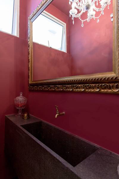 O banheiro de empregada deste ap&ecirc; foi aberto para o hall e virou um lavabo de impacto, com paredes na cor vinho. Projeto de Tria Arquitetura.