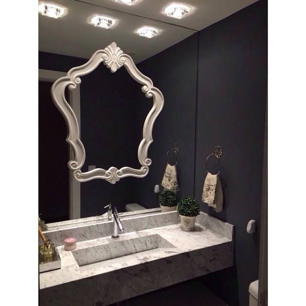 A parede escura n&atilde;o pesa no ambiente porque contrasta com a bancada de m&aacute;rmore e o gesso branco. A moldura sobre o espelho d&aacute; um efeito cl&aacute;ssico. Projeto de Marlon Behenck.