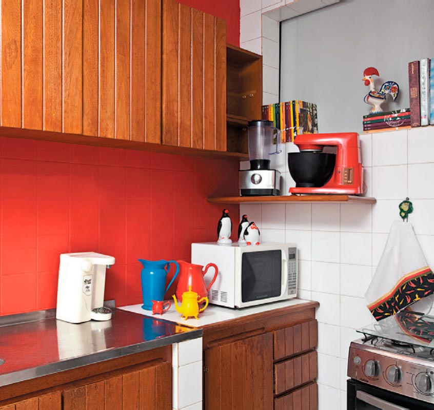 Jarras e a&ccedil;ucareiros velhinhos conquistaram visual pop na cozinha ap&oacute;s um banho de cor. Os azulejos brancos receberam uma camada de tinta vermelha, que contrastou com os arm&aacute;rios de madeira e com a geladeira de inox. Projeto de Valentina Rocha.