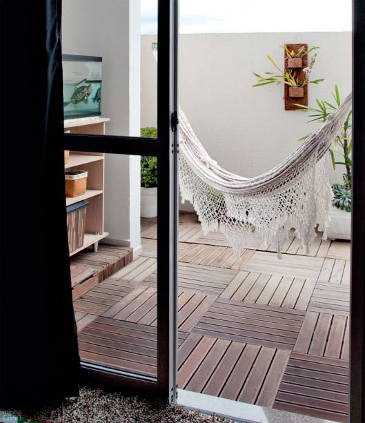 P&aacute;tio ecol&oacute;gico com rede. No ch&atilde;o deste p&aacute;tio que leva ao jardim, fica a caixa de capta&ccedil;&atilde;o de &aacute;gua das calhas de todo o pr&eacute;dio, por isso n&atilde;o era poss&iacute;vel assentar qualquer piso ali. Placas modulares apoiadas sobre uma camada de pedra brita resolvem a quest&atilde;o e resultam em um visual aconchegante. A rede, mais uma vez, criou uma &aacute;rea de relaxamento e pode ser montada e desmontada de acordo com o desejo do morador. O projeto &eacute; da decoradora Mariana Stella, de Curitiba.