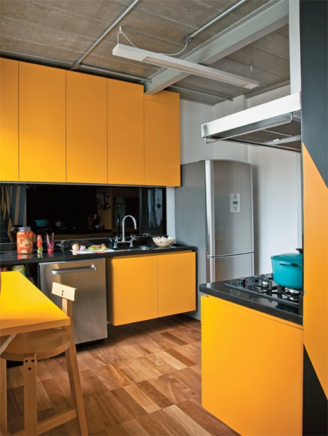 Desenhados pela arquiteta Suzana Barboza, a mesa dobrável e os armários da cozinha são de MDF revestido de laminado plástico amarelo. Na parede atrás da bancada de granito, o painel de vidro serigrafado preto (Divinal Vidros) arremata o conjunto.