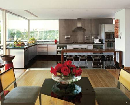 20 m&sup2;: Uma casa para conviver com os amigos. O pedido do casal definiu os espa&ccedil;os cont&iacute;nuos, marca do j&aacute; falecido autor &Aacute;lvaro Hardy, de Minas Gerais. A cozinha n&atilde;o podia escapar &agrave; premissa e, aberta para a &aacute;rea social, se mostra pr&aacute;tica e elegante, gra&ccedil;as ao dom&iacute;nio do granito preto e do a&ccedil;o inox. Eles se afinam com o assoalho de peroba-do-campo do living, diz a arquiteta Mariza Machado Coelho, co-autora do projeto. Divisor de &aacute;reas, o balc&atilde;o com cadeiras aramadas funciona como aparador e acomoda confortavelmente quem chega para almo&ccedil;os informais. Panos de vidro junto &agrave;s bancadas de trabalho permitem a comunica&ccedil;&atilde;o tamb&eacute;m com as varandas externas.
