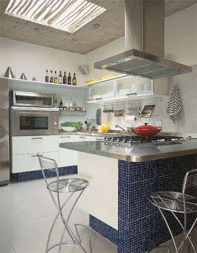 17 m&sup2;: Com azul-cobalto, pouco usual em cozinhas, os arquitetos Paulo Vilela e Paula Nicolini traduziram a originalidade previstapara este espa&ccedil;o gourmet em S&atilde;o Paulo. Sob a forma de pastilhas de vidro que revestem parte da bancada do fog&atilde;o e a base dos arm&aacute;rios, o tom se aliou ao branco e ao a&ccedil;o inox. Mas, como a composi&ccedil;&atilde;o poderia resultar fria, os profissionais resolveram lan&ccedil;ar m&atilde;o de toques r&uacute;sticos, impressos no piso de placas de travertino romano, devidamente impermeabilizadas, e no forro de tijolos aparentes. Este tem ainda um v&atilde;o central, onde duas folhas de vidro deixam passar luz natural, filtrada por tronquinhos de eucalipto.
