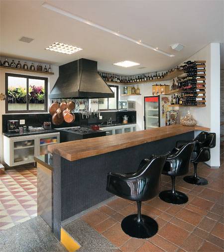 19 m&sup2;: Uma casa em volta da cozinha foi o pedido do conceituado chef mineiro Cantidio Lanna ao casal de arquitetos Joana e Tom&aacute;s Anastasia, de Belo Horizonte. Ele tamb&eacute;m exigiu lugar para fog&atilde;o e coifa industriais e para sua cole&ccedil;&atilde;o de conhaques, al&eacute;m de um forno de pizza. Rebaixado 20 cm em rela&ccedil;&atilde;o &agrave; sala, o piso de ladrilhos hidr&aacute;ulicos permite que o cozinheiro trabalhe de p&eacute;, no mesmo n&iacute;vel dos amigos, acomodados em confort&aacute;veis cadeiras com encosto. Assim a bancada de 70 cm de altura atende aos dois lados. Se o piso fosse nivelado, o balc&atilde;o teria de ter 90 cm, medida ideal para quem prepara a comida de p&eacute;, e os convidados precisariam se sentar em banquetas de bar, mais altas, diz Tom&aacute;s.
