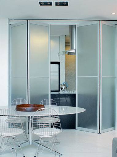 5 m&sup2;: Portas-camar&atilde;o de alum&iacute;nio e vidro italiano metalizado s&atilde;o o trunfo deste projeto assinado pelo arquiteto Sidney Quintela, de Salvador. Superatual, a cozinha permanece ora isolada, ora integrada &agrave; &aacute;rea social, conforme a abertura das esquadrias. Para os acabamentos, Sidney elegeu o requinte: o piso recebeu m&aacute;rmore branco, em placas de 1,30 x 1,30 m  o tamanho grande diminui a quantidade de emendas e cria maior unidade. Com granito preto absoluto, o arquiteto montou a estrutura e o tampo da bancada de trabalho, que, vista da sala de jantar, parece um bloco maci&ccedil;o. A pedra forma ainda um espelho que resguarda a parede ao lado da pia, coberta de pastilhas de vidro at&eacute; o teto.