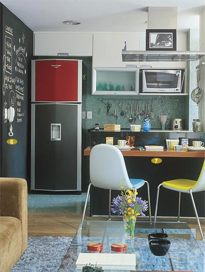 Apenas um balcão preto separa a sala da cozinha, neste apartamento de 68 m². Esta é a cor base da decoração, que ajuda na integração por estar nos dois ambientes. O casal de publicitários Fernando e Melissa Alves utilizaram detalhes coloridos para descontrair o espaço. Projeto dos arquitetos Ricardo Miura e Carla Yasuda.