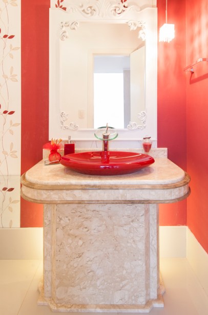 Para fazer o lavabo da casa do cantor Mateus (da dupla Jorge e Mateus), a arquiteta Letícia Alves utilizou a cor preferida do músico: o vermelho. O papel de parede com um floral 3D se mistura à pintura. As demais paredes receberam tinta na cor branco neve com acabamento acetinado. O piso é porcelanato (60 x 60 cm) e o rodapé, de 30 cm de altura, protege o papel de parede. A bancada é feita de mármore bege com detalhes em marrom. Sanca, pendente com cristais na lateral da bancada e fitas de LED atrás da coluna formam o projeto de iluminação do espaço de 1,20 x 2,55 m. A residência é em Itumbiara (GO).