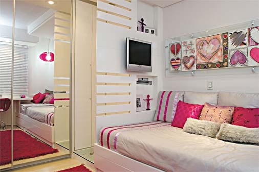 Bicama para receber as amigas, armários amplos para guardar muita roupa e a cor pink pincelada em todo o ambiente de 13,5 m². "Os desejos da moradora, de 17 anos, foram plenamente satisfeitos", relata a designer de interiores Marcela Franchini. Como o tom era o mais importante, vários elementos fizeram a diferença: sobre a colcha neutra de microsseda matelassada foram aplicadas fitas de cetim em vários matizes de rosa. Almofadas de diversos tamanhos e formas trazem conforto. O tapete felpudo contrasta com o piso claro. No reflexo do espelho que reveste a porta do armário, se vê a bancada de estudos.