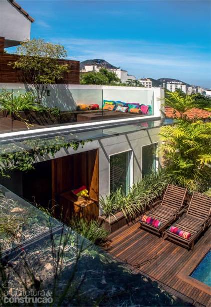 Sob medida para proteger a varanda, o beiral de 80 cm foi montado com vidro laminado incolor (10 mm) e apoiado em estrutura de alum&iacute;nio com acabamento de a&ccedil;o corten (se&ccedil;&otilde;es de 1 m, execu&ccedil;&atilde;o da Bergel). Cabos de a&ccedil;o encapados servem de guia para a trepadeira sapatinho-de-judia. Almofadas da Lisa Corti. Projeto do arquiteto Erick Figueira de Mello.