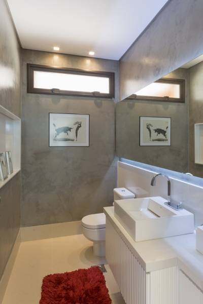 O lavabo recebeu uma tinta que imita a textura de cimento queimado. O nicho em frente ao espelho &eacute; feito de quartzo (Fantastic White).