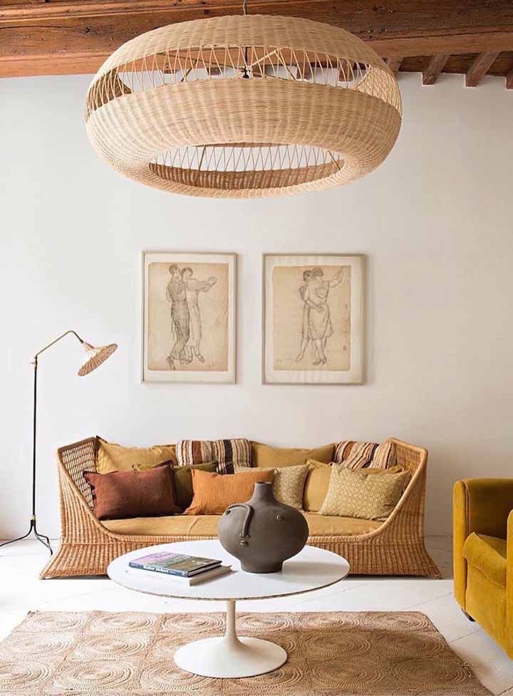 Os tons terrosos e os m&oacute;veis com fibras naturais chamam a aten&ccedil;&atilde;o nesta sala. O teto em madeira refor&ccedil;a o aspecto r&uacute;stico do espa&ccedil;o e combinado a enorme lumin&aacute;ria em vime confere personalidade. A luz natural abundante faz a sala ficar ainda mais convidativa.