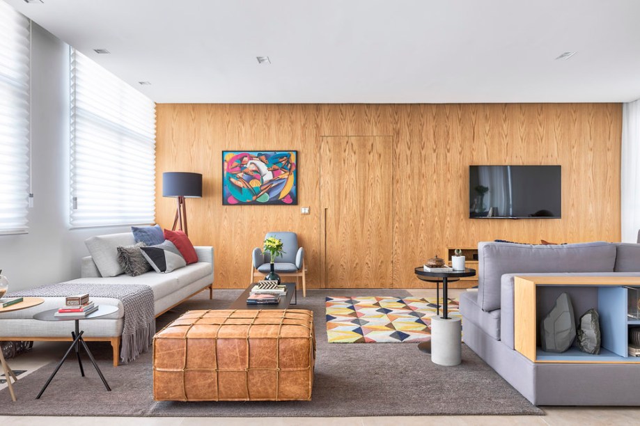 A sala e seu painel em madeira, que esconde a porta que dá acesso à área íntima do apartamento. A sala e seu painel em madeira, que esconde a porta que dá acesso à área íntima do apartamento.