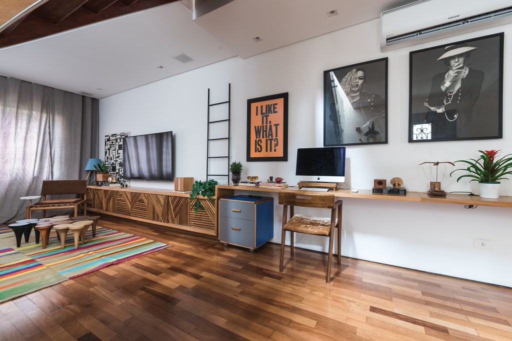 Sala de estar com paredes brancas, piso de madeira e rack de madeira.