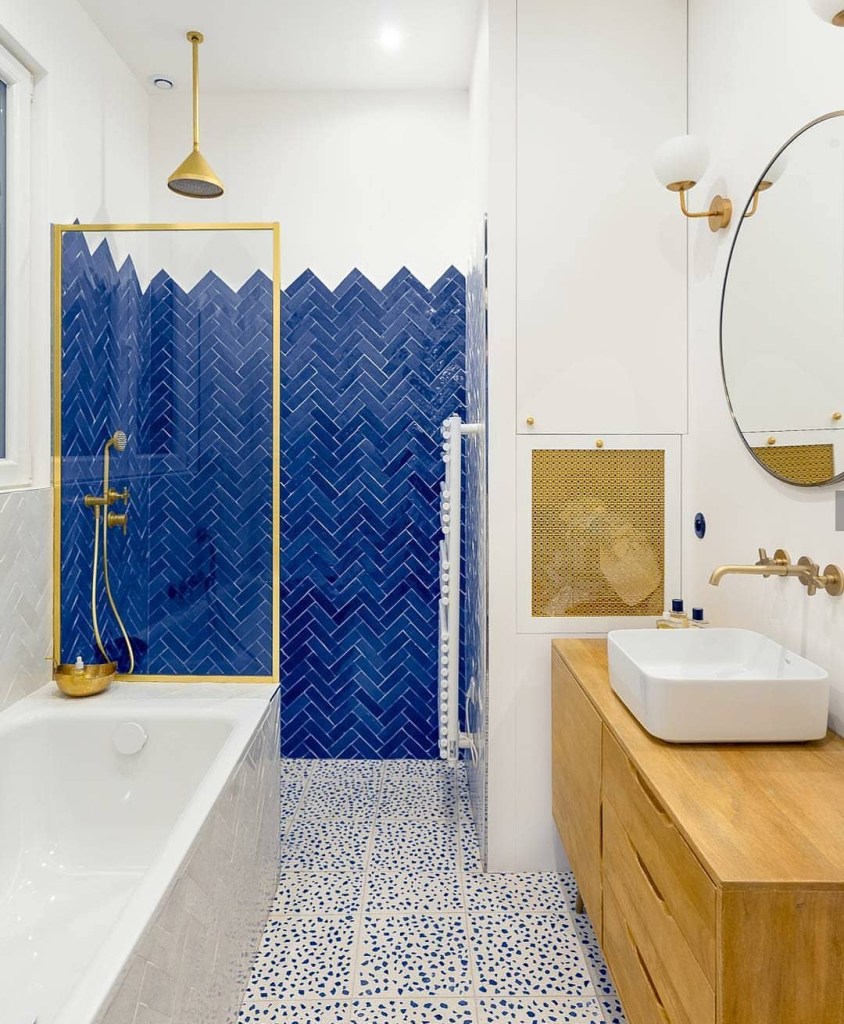 banheiro com revestimentos azuis e metais dourados
