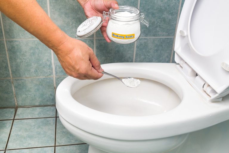 Como desentupir vaso sanitário: 7 formas de resolver o problema. Pessoa colocando bicarbonato em vaso sanitário.