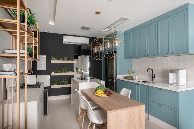 Neste loft com 40m², os armários superiores da cozinha foram projetados na cor azul petróleo e estão localizados acima da pia da geladeira, possibilitando uma melhor organização dos utensílios no projeto de interiores realizado pelas profissionais do escritório Meet Arquitetura Neste loft com 40m², os armários superiores da cozinha foram projetados na cor azul petróleo e estão localizados acima da pia da geladeira, possibilitando uma melhor organização dos utensílios no projeto de interiores realizado pelas profissionais do escritório Meet Arquitetura