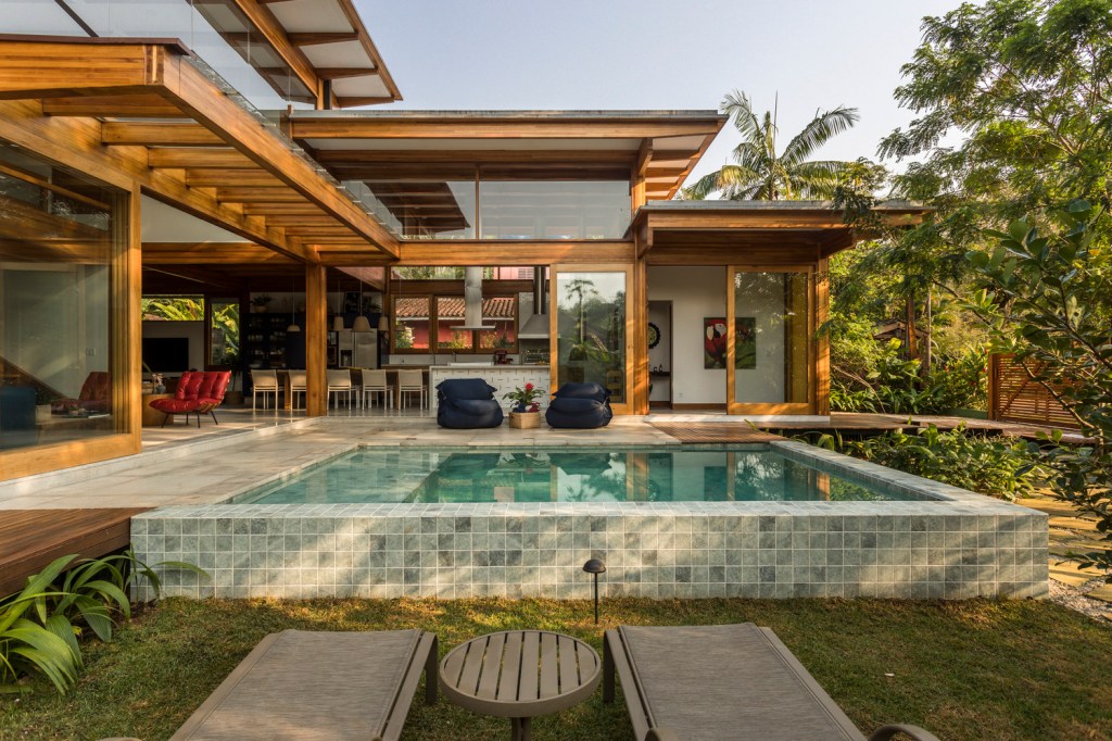 1-casa-de-236-m-2-integra-ambientes-e-traz-a-natureza-para-interior Área externa de casa com piscina e bastante natureza