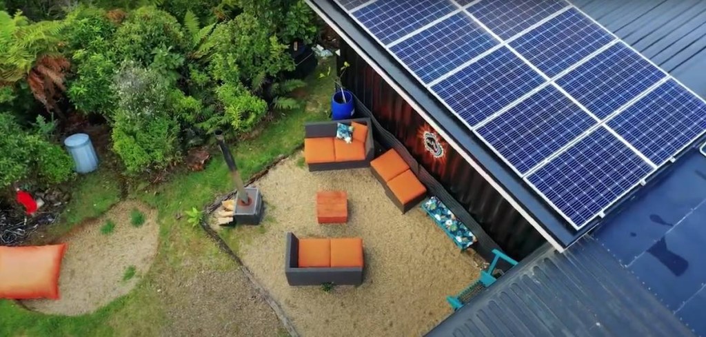 Foto aérea do fundo da casa com espaço de convivência com sofás e horta