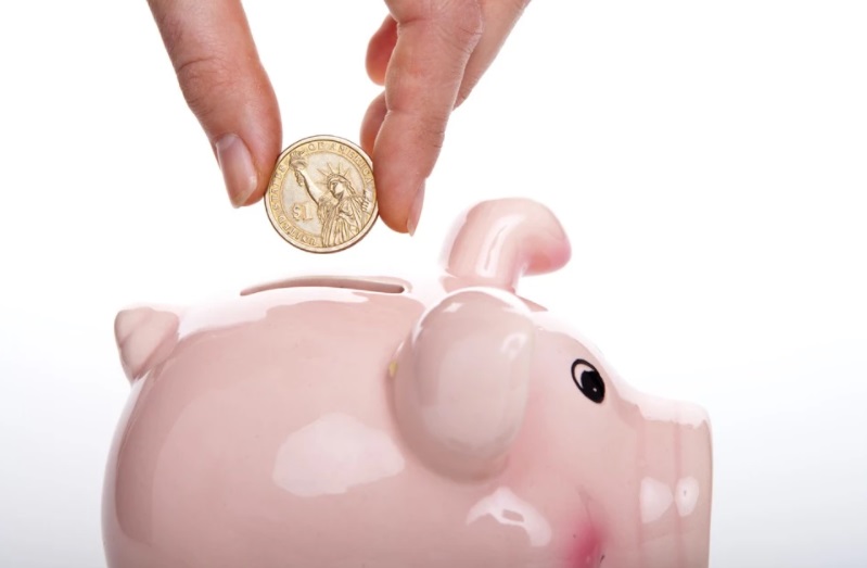Cofre de porquinho rosa com moeda sendo colocada