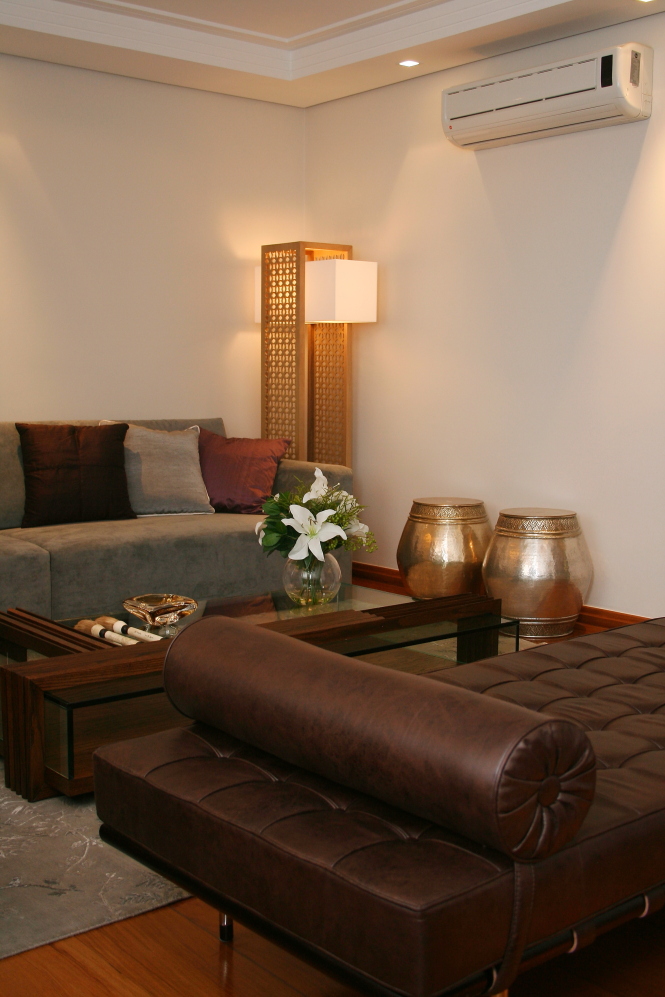 Sala de estar com sofás cinza e de couro marrom, com luminária de chão com cor amarelada