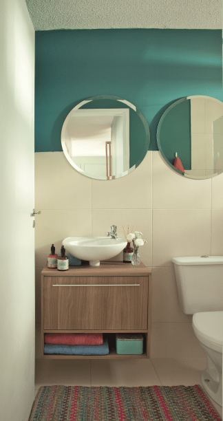 Neutro, o &uacute;nico banheiro do ap&ecirc; n&atilde;o precisou de muito para ficar charmoso: bastaram algumas pinceladas de azul, um gabinete sob medida e espelhos redondos. Projeto da designer de interiores Maria Veridiana Leoni, da M2House, e do arquiteto Kennory Weston, KW Arquitetura.