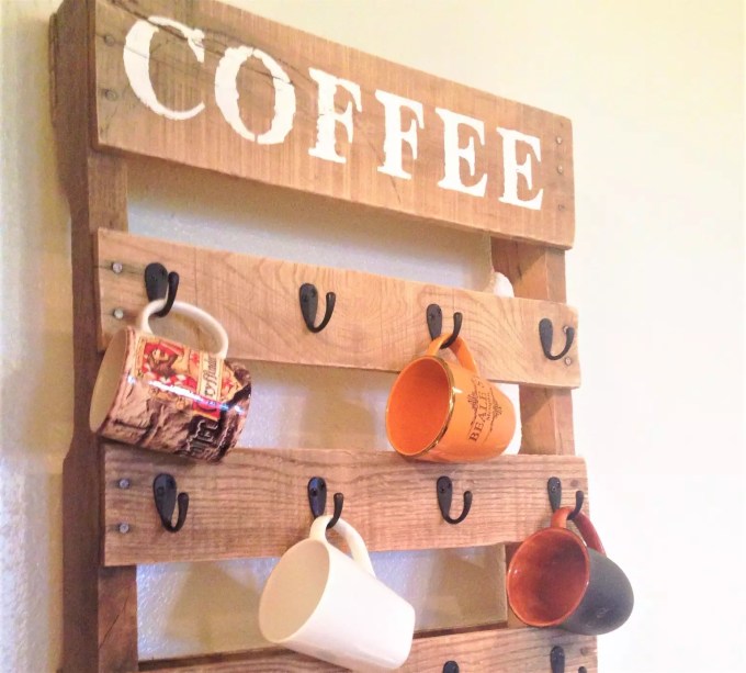 Suporte de canecas – Desenvolva suas habilidades de criação com este projeto DIY de um dia. Comece com o pallet de madeira mais limpo, corte-o em um tamanho menor e adicione ganchos de metal. O logotipo "Café" foi feito usando um estêncil, tinta e uma esponja de tinta.