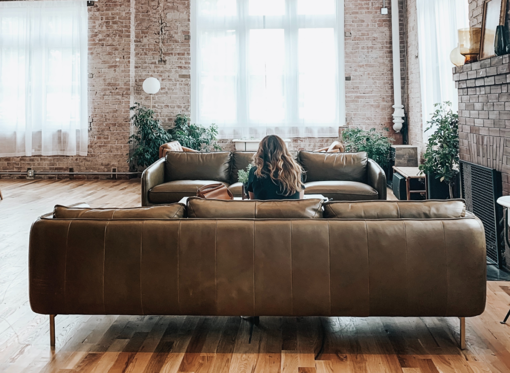 6-como-fazer-a-decoração-de-um-loft-industrial Mulher sentada em sofá marrom em loft industrial