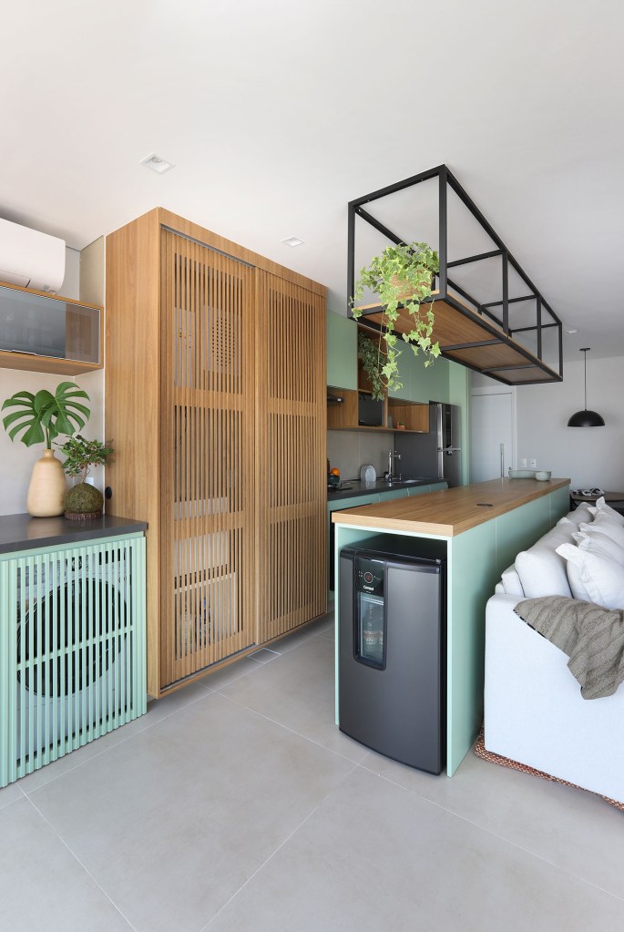 reforma-aumenta-espaco-de-armazenamento-em-ape-de-70-m²-casa.com-lilutz-arquitetura-mariana-orsi-16 Armários feitos de madeira ripada para esconder produtos de limpeza e lavanderia, em varanda e cozinha integrada