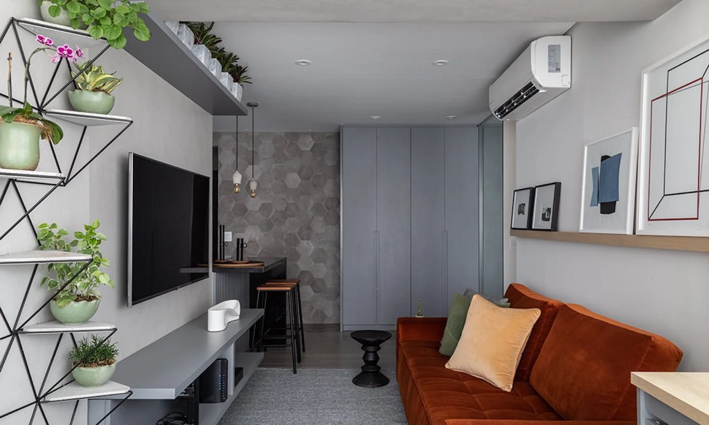 Sala de estar pequena em estilo industrial com sofa vermelho e parede revestida em cimento
