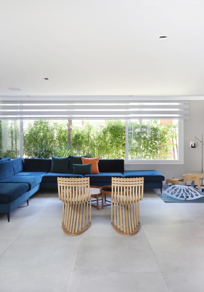4-minimalismo-contemporaneo-e-moderno-se-misturam-nesta-casa-de-350-m-2 Sala com sofá azul em L, janelas grandes voltadas à natureza e cadeiras em tons neutros