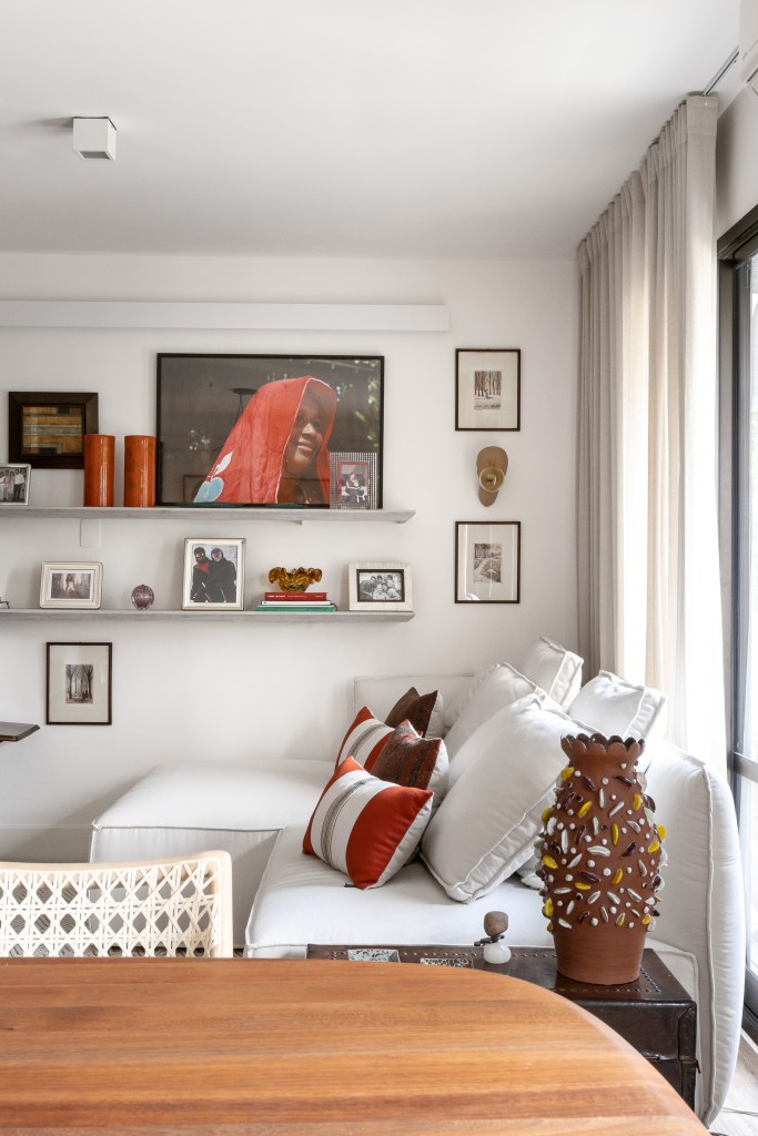 Projeto Terça Arquitetura – Itaim Bibi I Foto Manuel Sá (21)-mesa-quadros Estar com sofá branco; mesinha de centro circular em madeira; prateleiras com quadros
