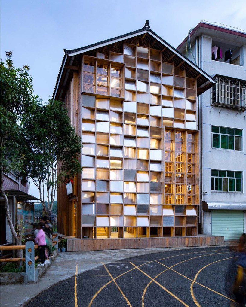 Fachada luminosa de biblioteca comunitária com painéis de policarbonato translúcidos.