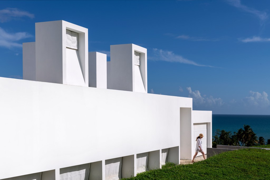 Exterior de uma casa toda branca em que não se consegue distinguir janelas ou qualquer abertura.