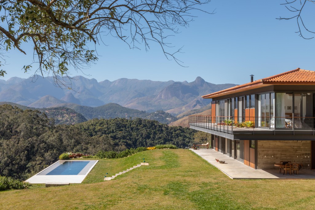 Casa de madeira e vidro em meio à serra