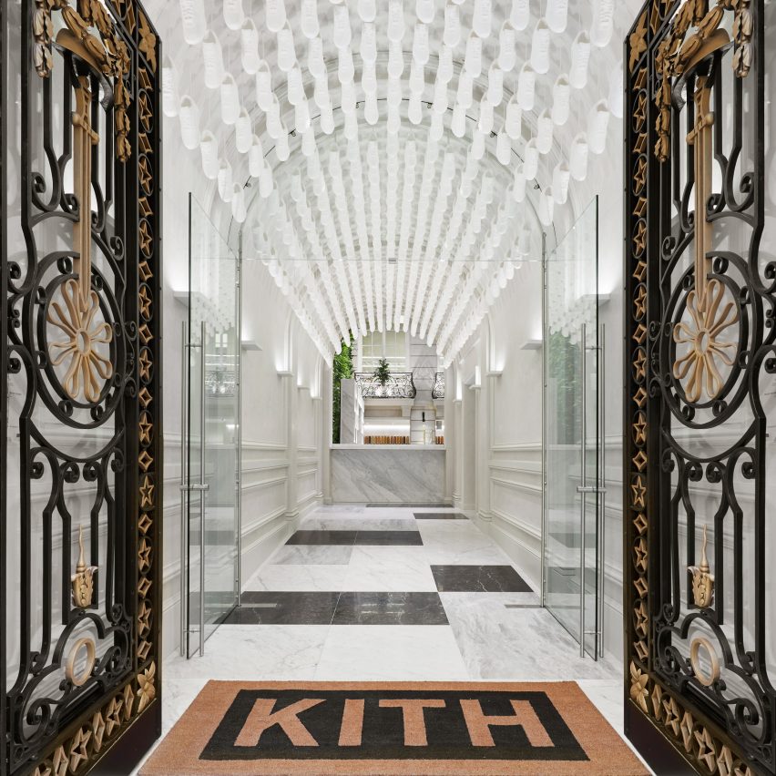 Hall de entrada com teto em curva coberto por tênis Nike brancos.