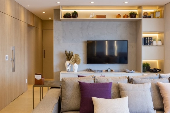 Saiba-como-decorar-a-sala-de-TV-ideal (2) Sala de estar com sofá em primeiro plano. Atrás do móvel fica o espaço da sala de TV, esta fica fixa na parede.