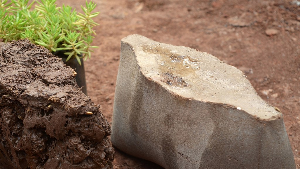10-materiais-que-podem-mudar-a-construção-divulgação-dezeen-tijolo-de-bucha-de-carvão Foto mostra tijolo em formato oval em tom de areia sobre piso de terra.
