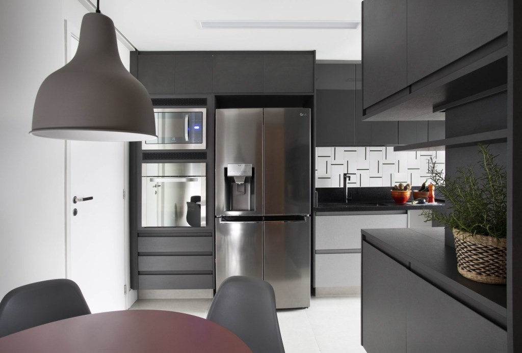 Apartamento- Barra da Tijuca- BETA ARQUITETURA Cozinha com armários em preto opaco, detalhes geométricos na parede e duas gavetas em cinza-claro
