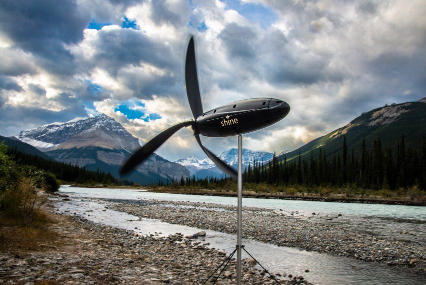 Turbina do tamanho de uma garrafa de 1 litro sobre um tripé metálico em meio a uma paisagem montanhosa.