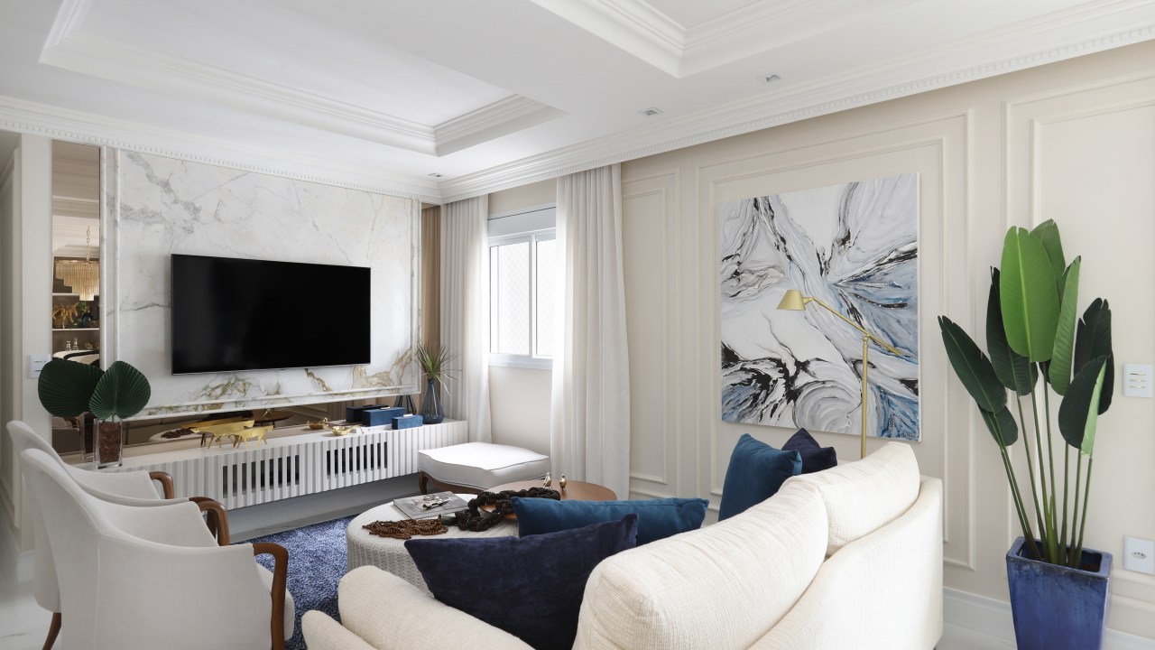 Sala de estar com tv; poltronas; sofás; boiseries e quadro