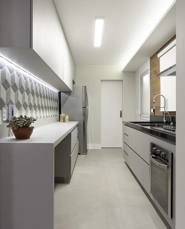 como-usar-fitas-led-5-ambientes-Suellen-Figueiredo-Landhi-Reprodução-cozinha-bancada-fita-led Foto mostra cozinha com bancada em que se vê fita led logo abaixo dos armários aéreos, iluminando área de trabalho e preparo dos alimentos.