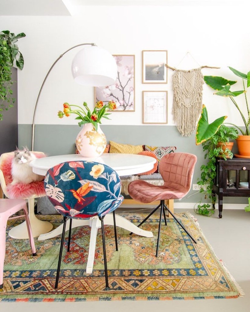 Sala de jantar em estilo boho; mesa redonda; quatro cadeiras estampadas; plantas e luminária de piso