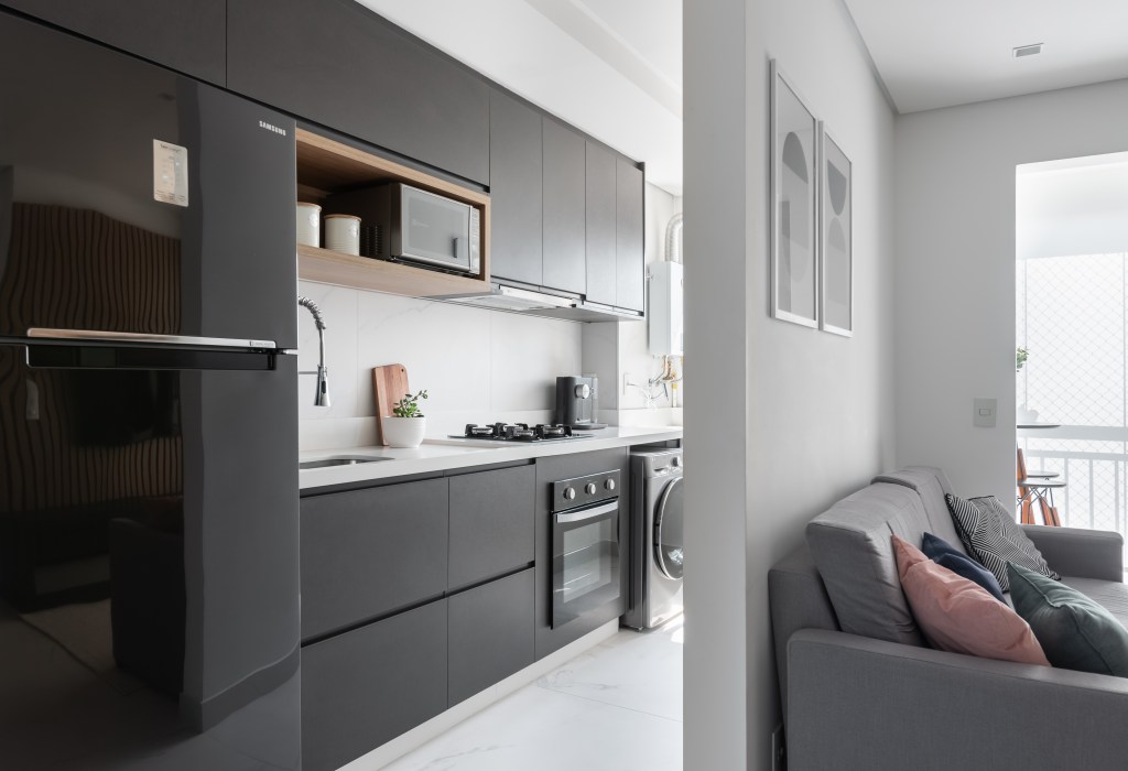 Ape-de-50-m2-possui-decoracao-simples-mas-eficaz-projeto-MTA-arquitetura-foto-Ana-Helena-Lima-cozinha-integrada-lavanderia-geladeira-marcenaria-preto Cozinha com marcenaria e geladeira preta