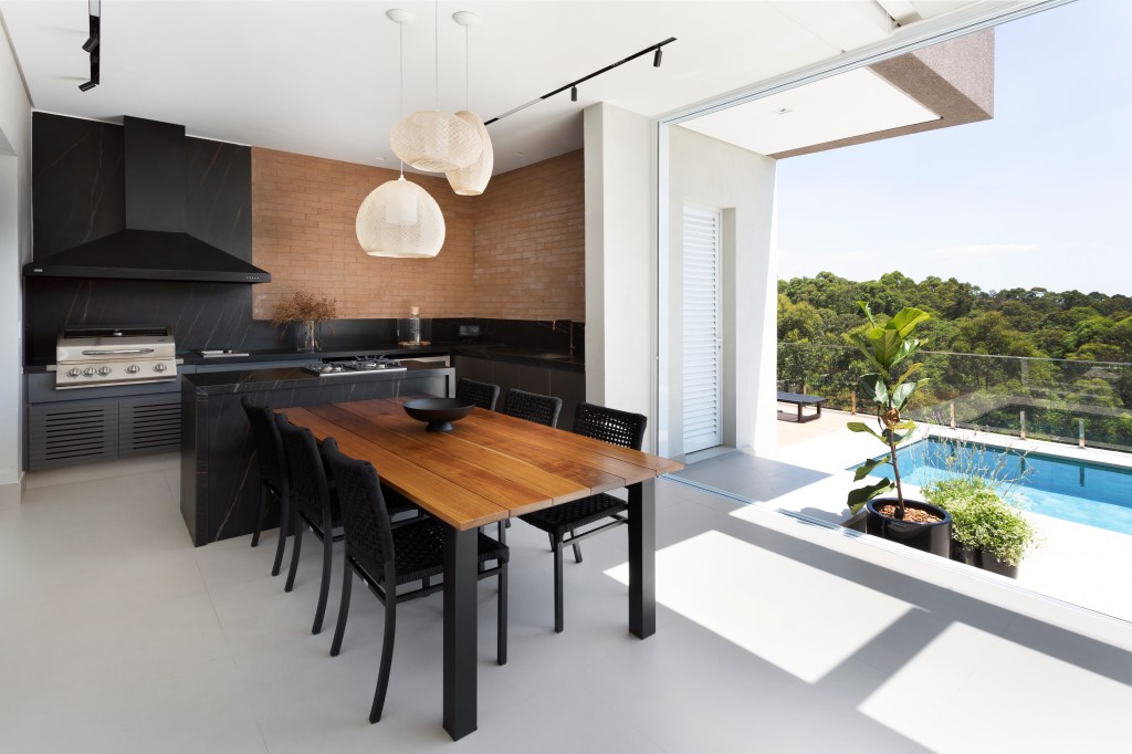 Casa-de-580-m²-destaca-a-paisagem-e-valoriza-a-natureza-projeto-Studio-Deux-Julia-Ribeiro-area-gourmet-churrasqueira-piscina Luminárias de destaque em mesa de churrasqueira