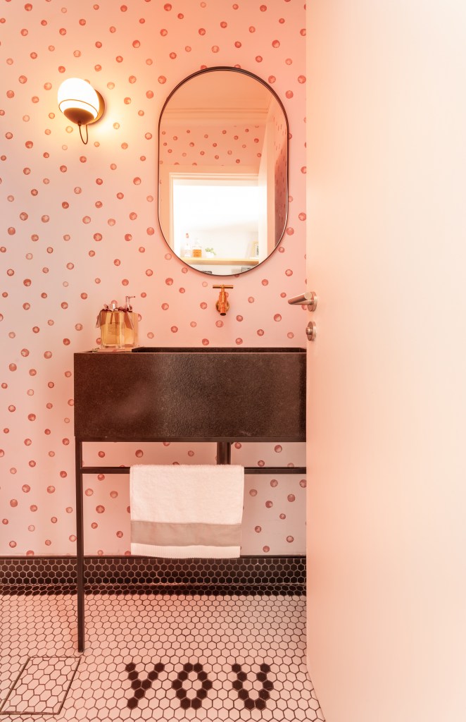 Lavabo com piso de pastilhas e papel de parede com bolinhas rosa