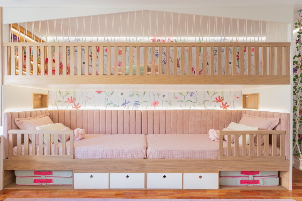 quarto-beliche-ll-arquitetura-credito-kelly-queiroz Trazendo um mundo do faz de conta para o quarto das meninas, a LL Arquitetura e Interiores projetou um espaço com uma atmosfera que parece ter saído de livros infantis para as irmãs de 3 e 7 anos. O diferencial é o design da cama beliche: a arquiteta aproveitou a parede lateral de 5 m de comprimento para criar uma grande casa alusiva à casa na árvore. As duas camas ficam no primeiro nível da “beliche”. Acima das camas, um espaço para brincar de casinha ou cabaninha e que também pode receber amigas para dormir.