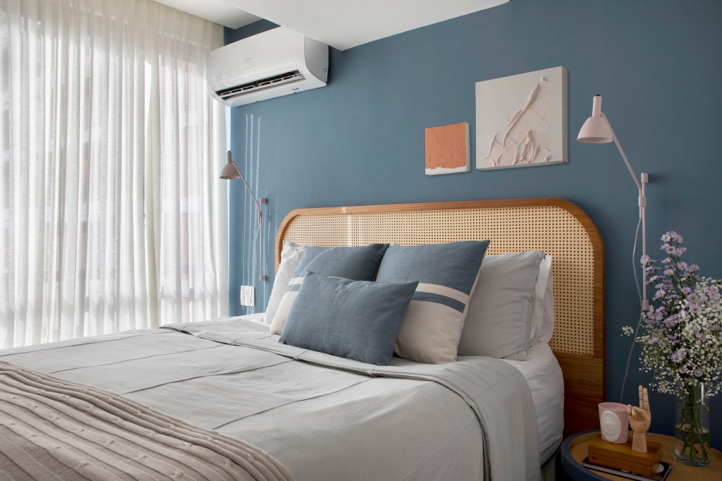 Quarto com cama de casal e parede azul. Cabeceira de treliça.