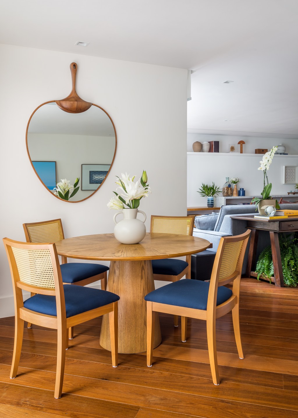 Sala de jantar com mesa redonda em madeira e espelho